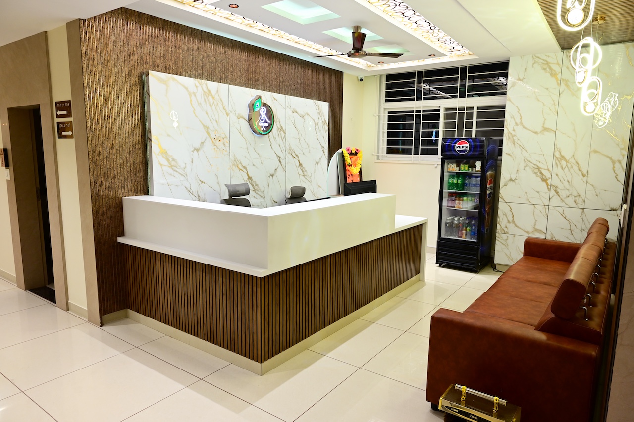 SR Grand Hotel Tumkur room showing amenities — Smart TV, AC, tea maker, and complimentary water